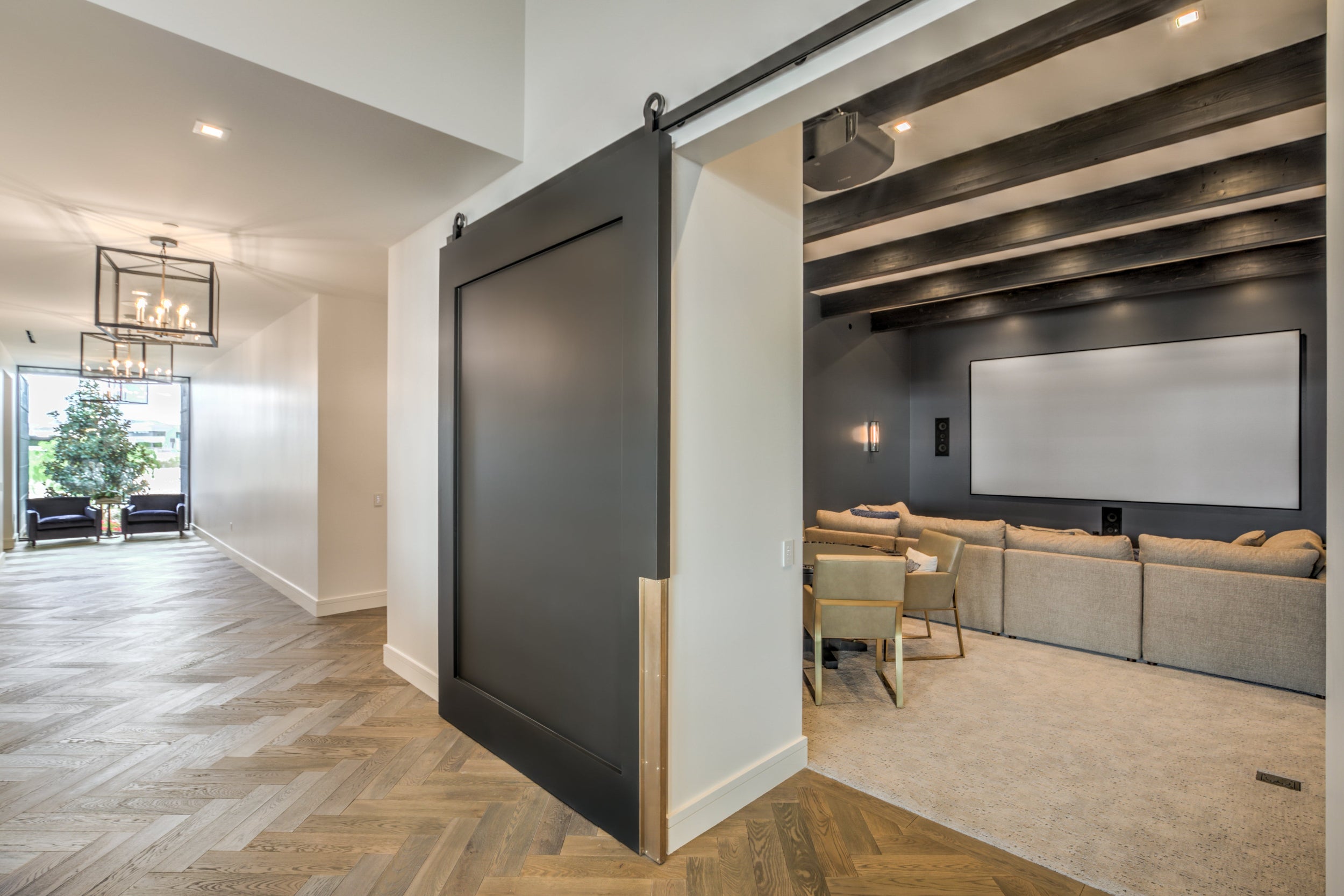 Modern interior with a sliding barn door separating a living room from a home theater.