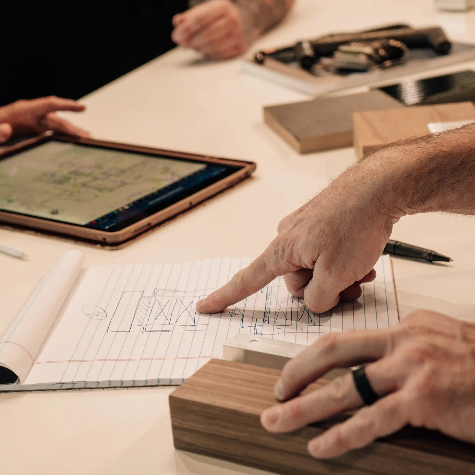Two people working together at a table with a tablet and documents.